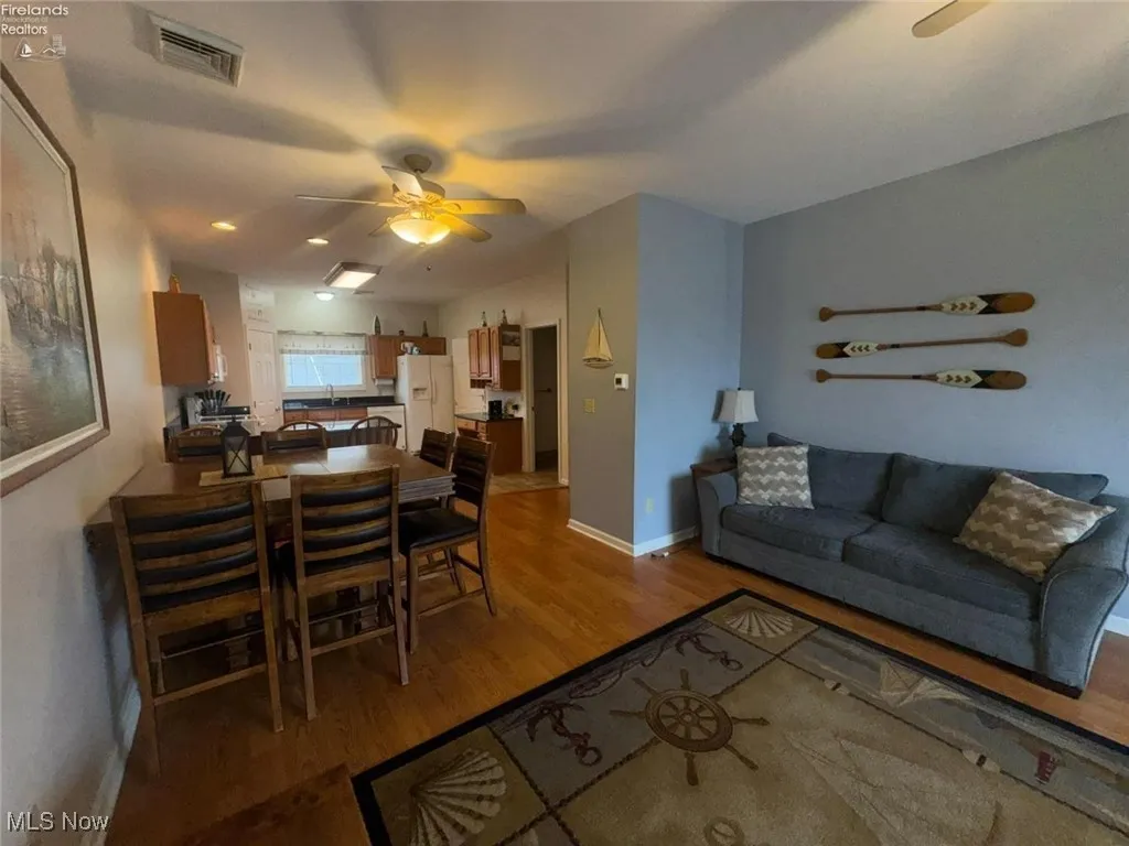 Living room featuring light wood-type flooring, ceiling fan, and baseboards