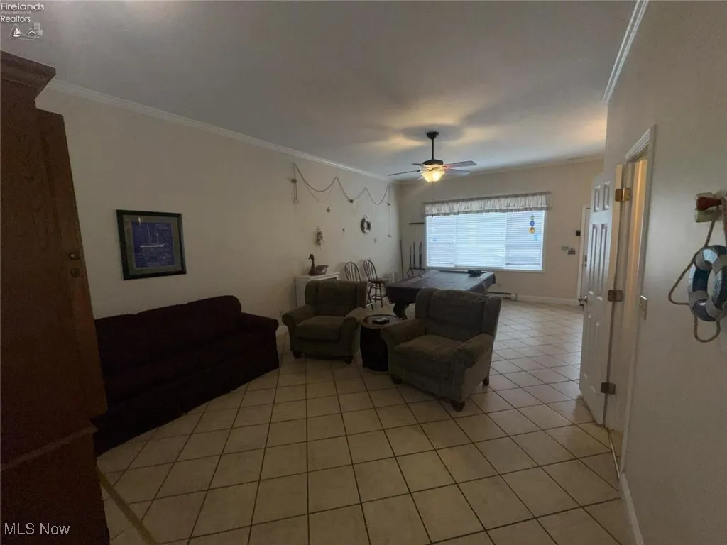 Living room featuring ornamental molding, light tile patterned floors, and ceiling fan