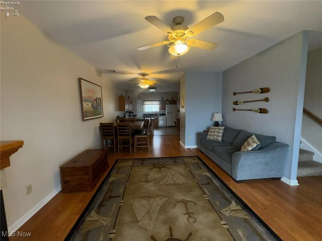 Living area featuring wood finished floors, ceiling fan, stairway, and baseboards