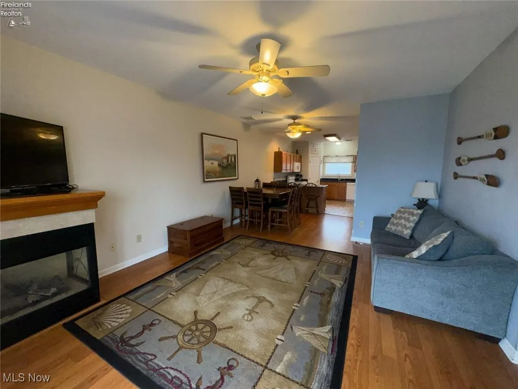 Living room featuring a ceiling fan, wood finished floors, a fireplace, and baseboards