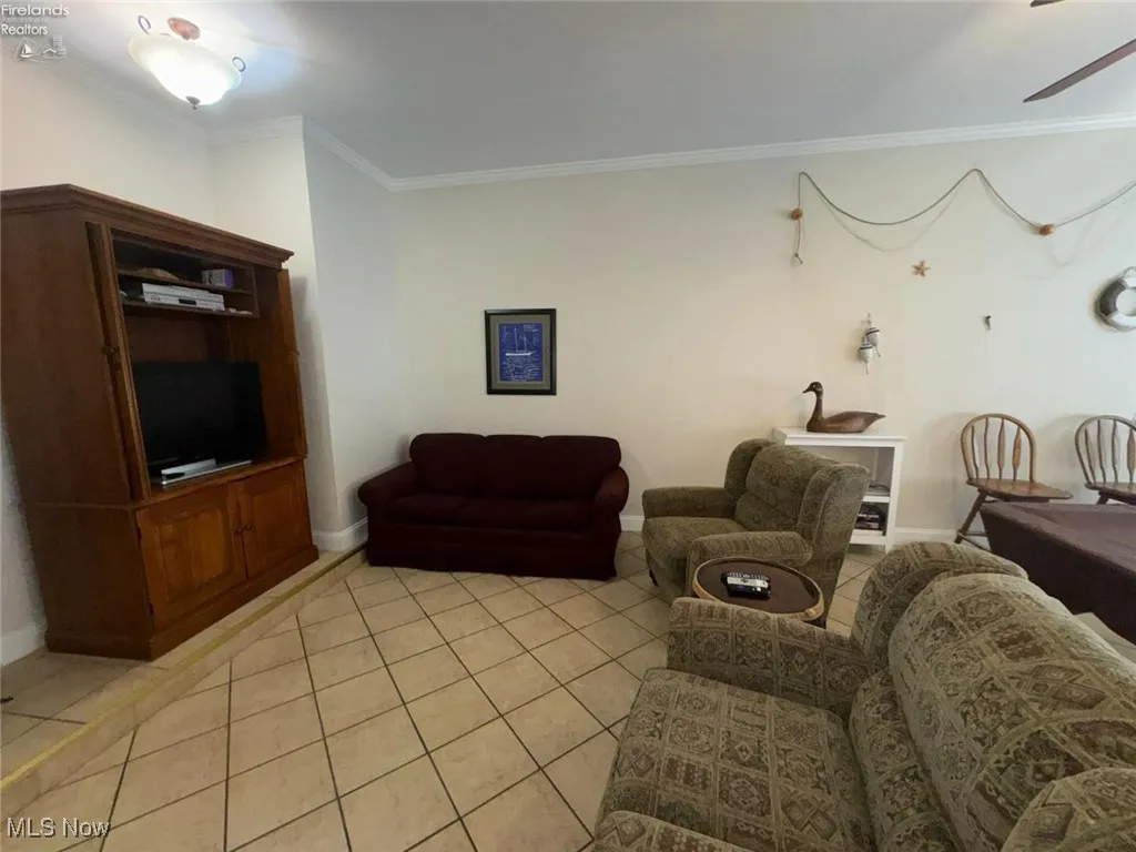 Living area with ornamental molding, light tile patterned floors, ceiling fan, and baseboards