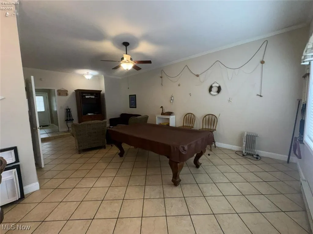 Recreation room featuring light tile patterned floors, pool table, radiator heating unit, ceiling fan, and ornamental molding