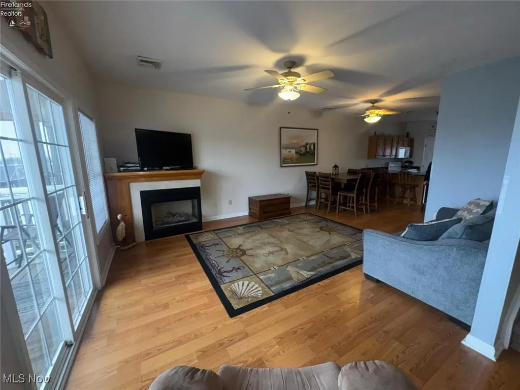Living area featuring plenty of natural light, wood finished floors, a ceiling fan, and a fireplace