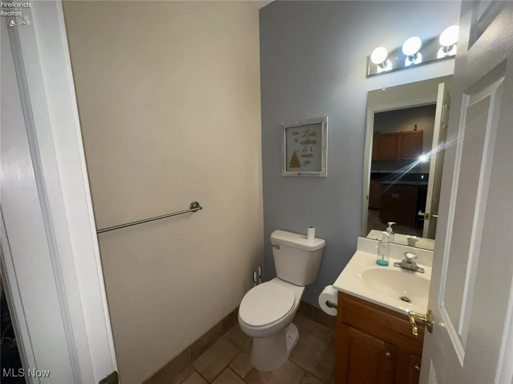 Bathroom featuring vanity, tile patterned flooring, toilet, and baseboards
