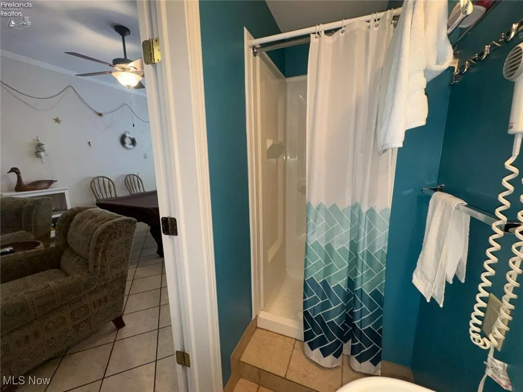 Bathroom with a shower stall, ceiling fan, tile patterned flooring, and ornamental molding