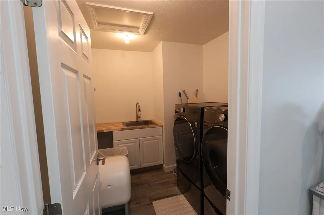 Washroom with cabinet space, washing machine and dryer, dark wood-type flooring, and attic access