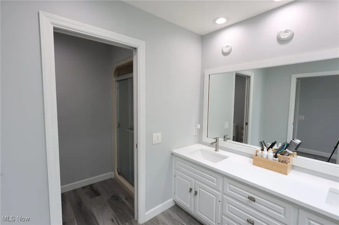 Bathroom with vanity, a shower stall, wood finished floors, and baseboards