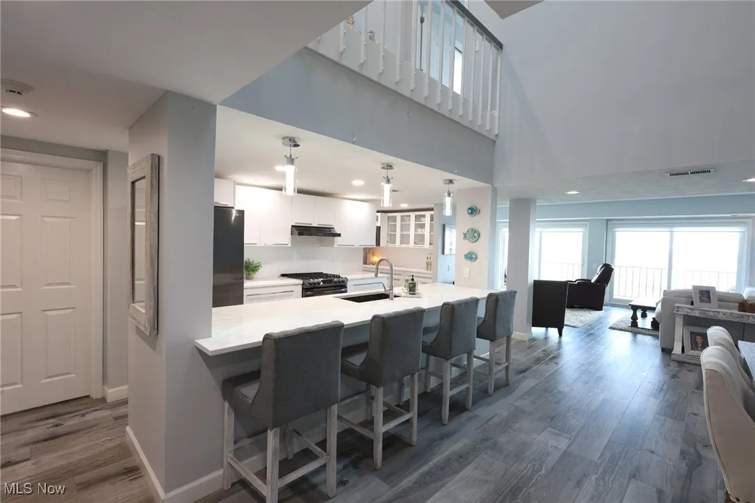 Kitchen with freestanding refrigerator, a sink, baseboards, white cabinets, and recessed lighting