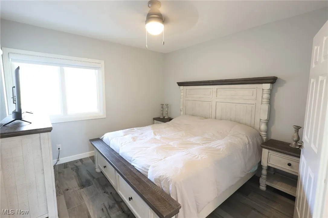 Bedroom with dark wood finished floors, baseboards, and a ceiling fan