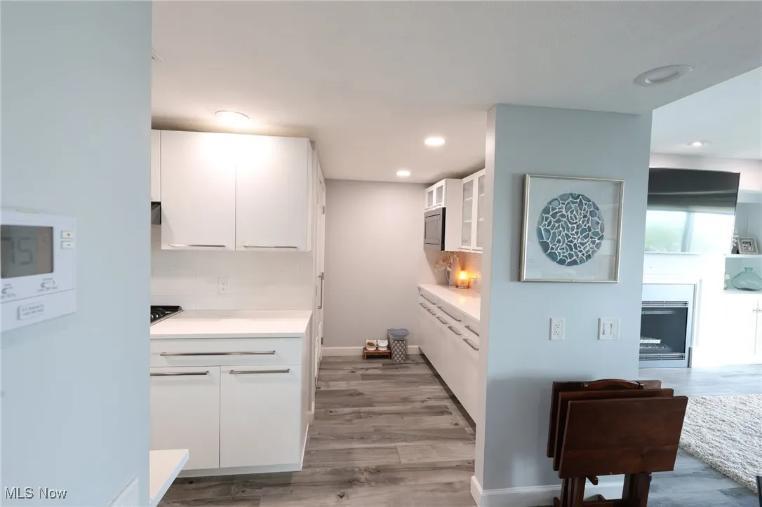 Kitchen featuring white cabinetry, backsplash, light wood-style flooring, light countertops, and recessed lighting