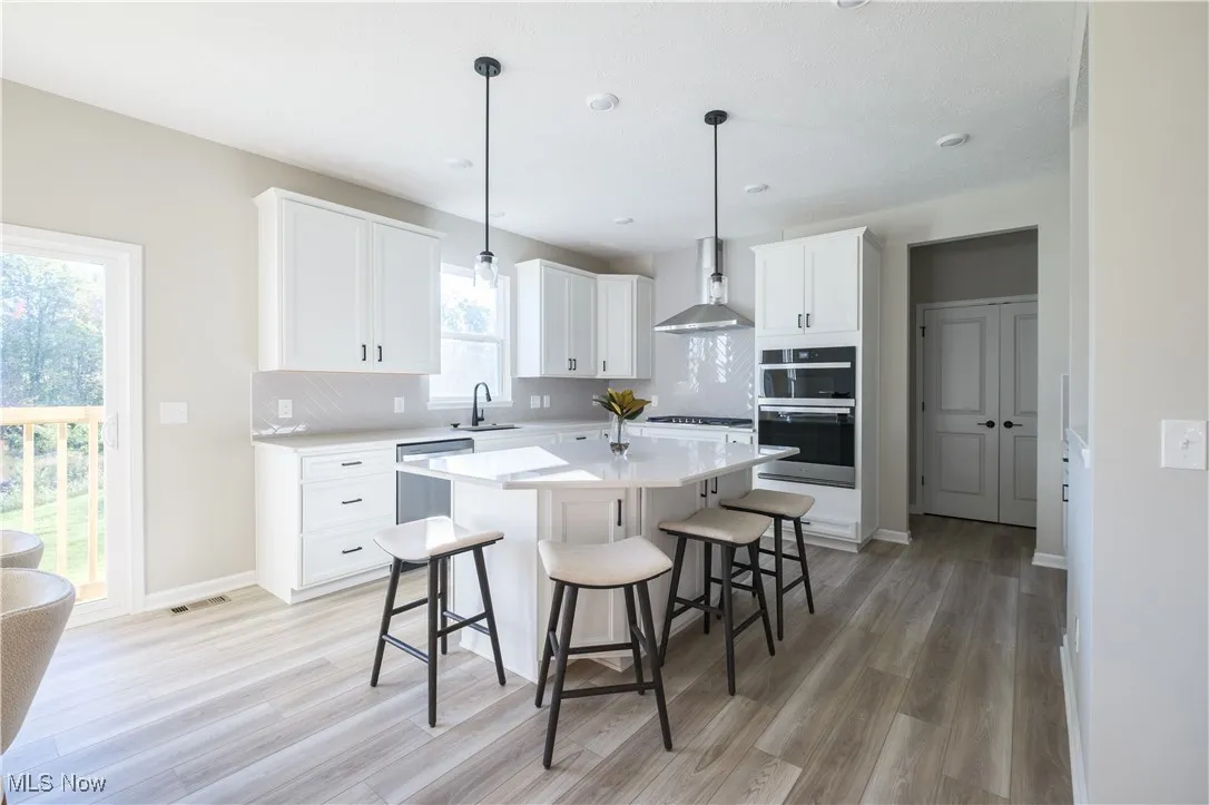 Kitchen featuring a breakfast bar area, pendant lighting, light wood-style flooring, white cabinets, and recessed lighting