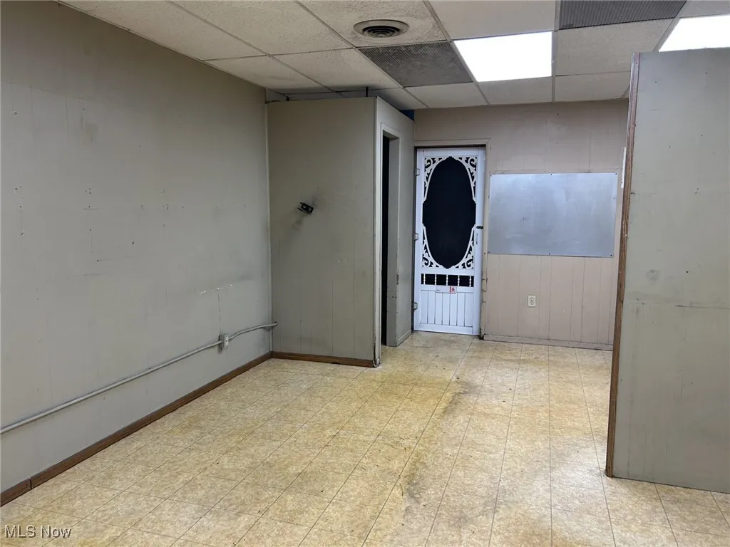 Spare room with tile patterned floors and a paneled ceiling