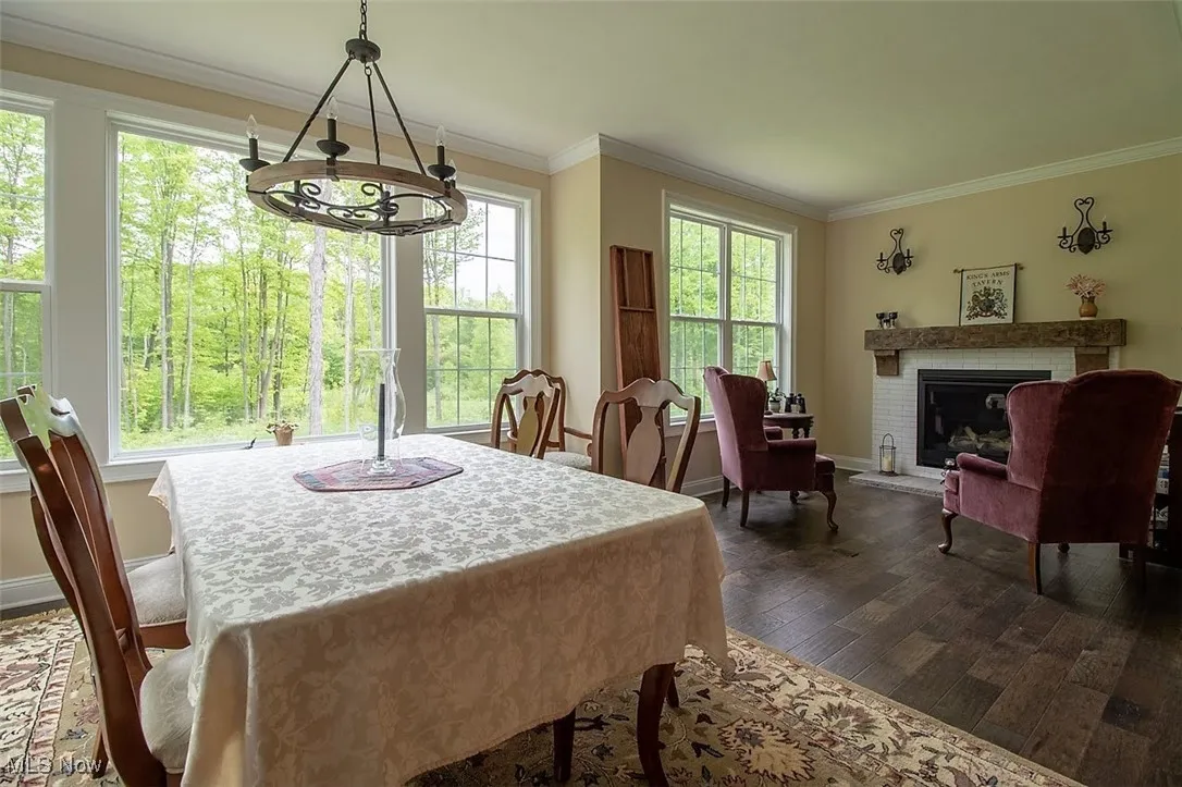Virtually staged Dining space adjacent to the kitchen featuring plenty of natural light and dark hardwood flooring, open to the greatroom as well as hearth room and great views of the woded lot