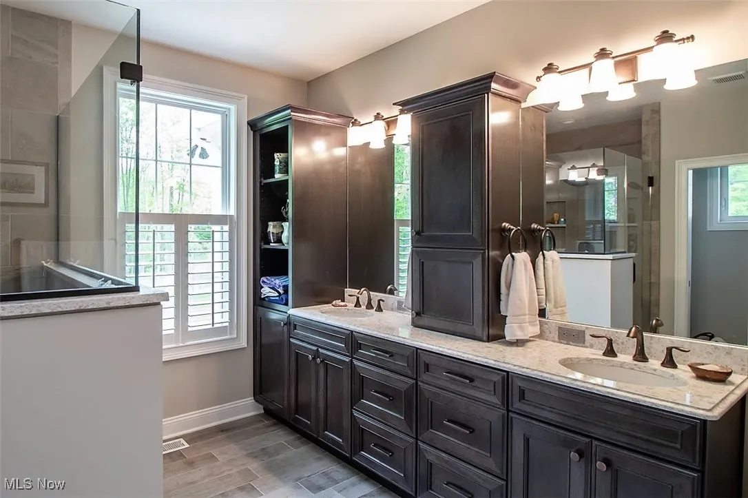 Virtually staged Master Bathroom featuring a shower with door, and dual sinks