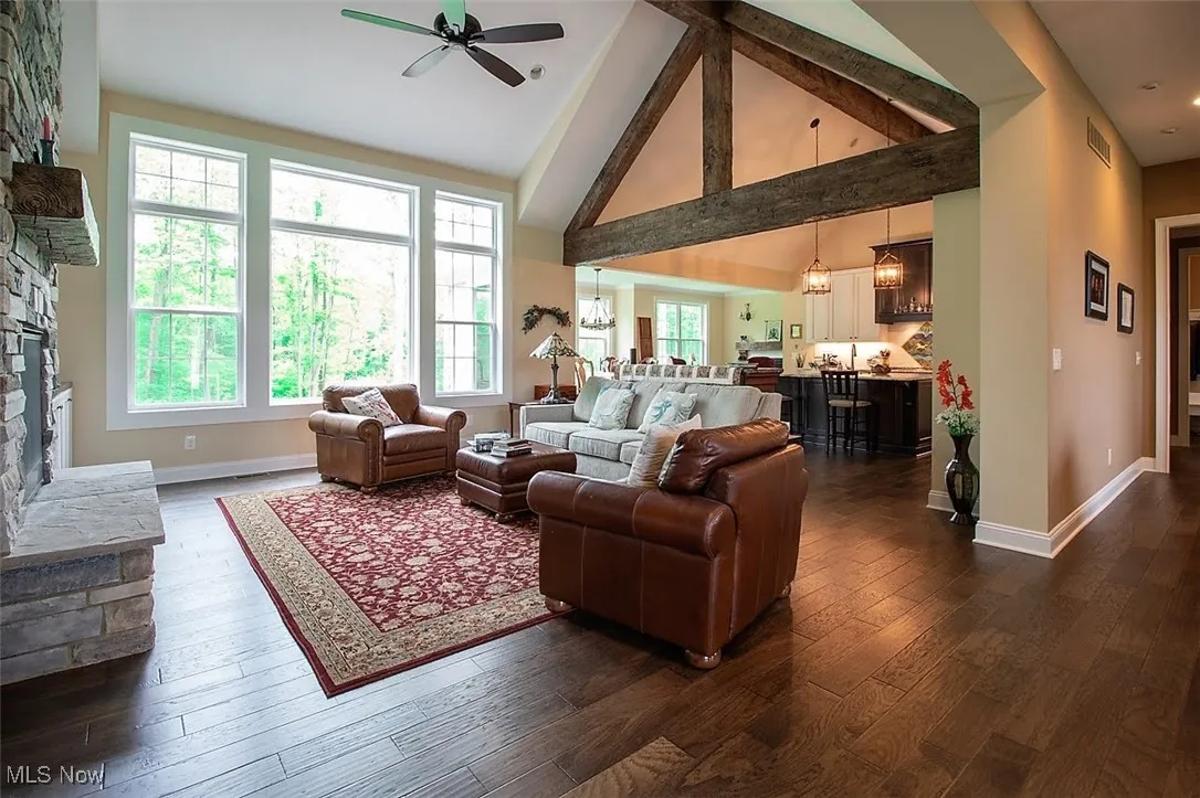 Virtually staged Great room featuring dark hardwood / wood-style floors, high vaulted ceiling, and a fireplace