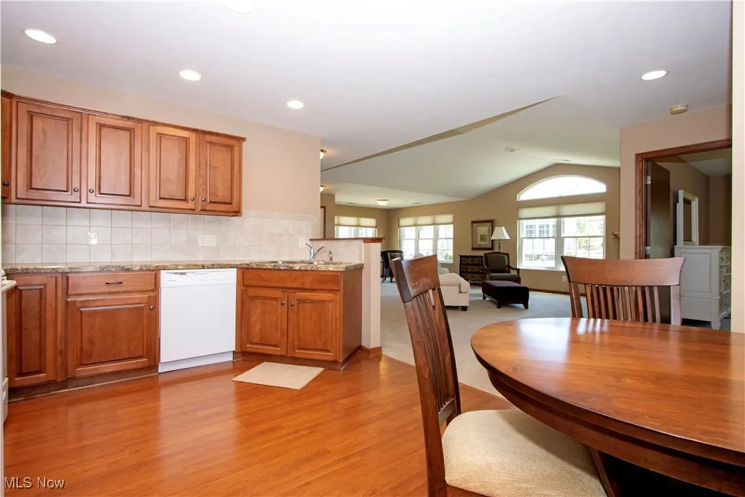 Kitchen with white dishwasher, light wood finished floors, a peninsula, brown cabinetry, and open floor plan