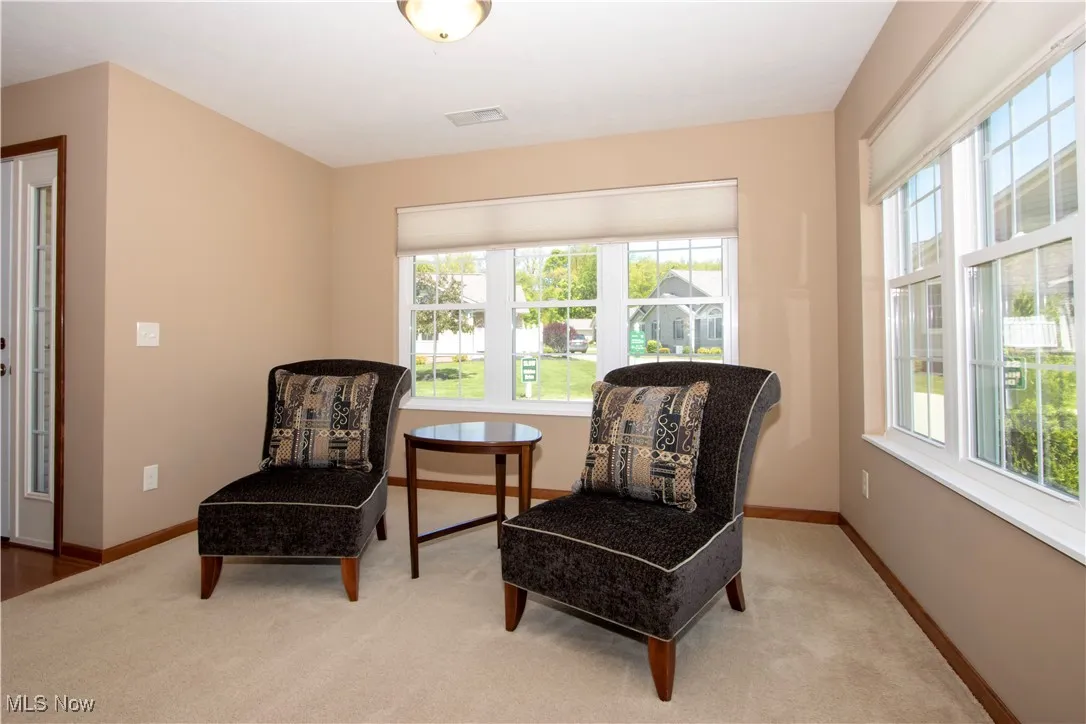 Sitting room featuring healthy amount of natural light, carpet, and baseboards