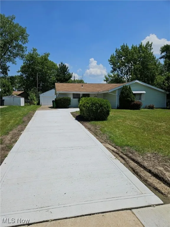 Ranch-style home with a front yard and concrete driveway