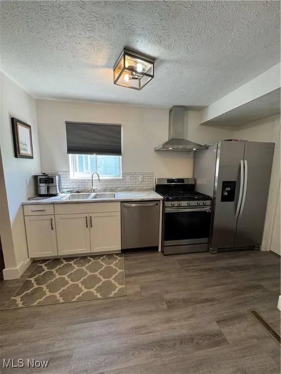 Kitchen with dishwasher, stove, extractor fan, a sink, and fridge