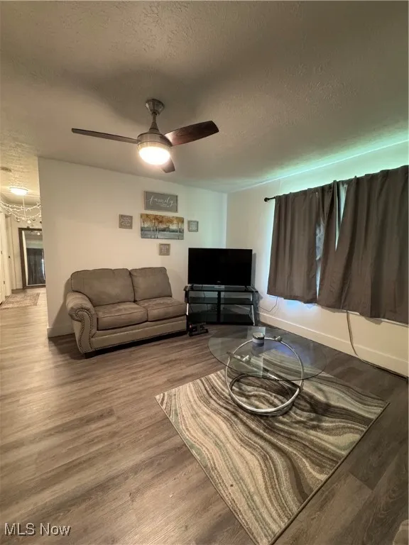 Living area with a textured ceiling, wood finished floors, and a ceiling fan