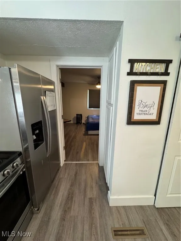 Hallway featuring dark wood-style flooring, a textured ceiling, and baseboards