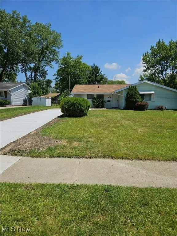 View of front of house with concrete driveway and a front yard
