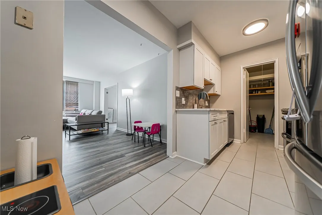 Kitchen with stainless steel fridge, light countertops, white cabinetry, open floor plan, and electric cooktop