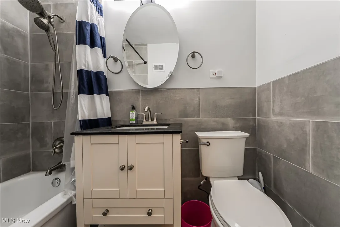 Bathroom with tile walls, vanity, and shower / bath combo