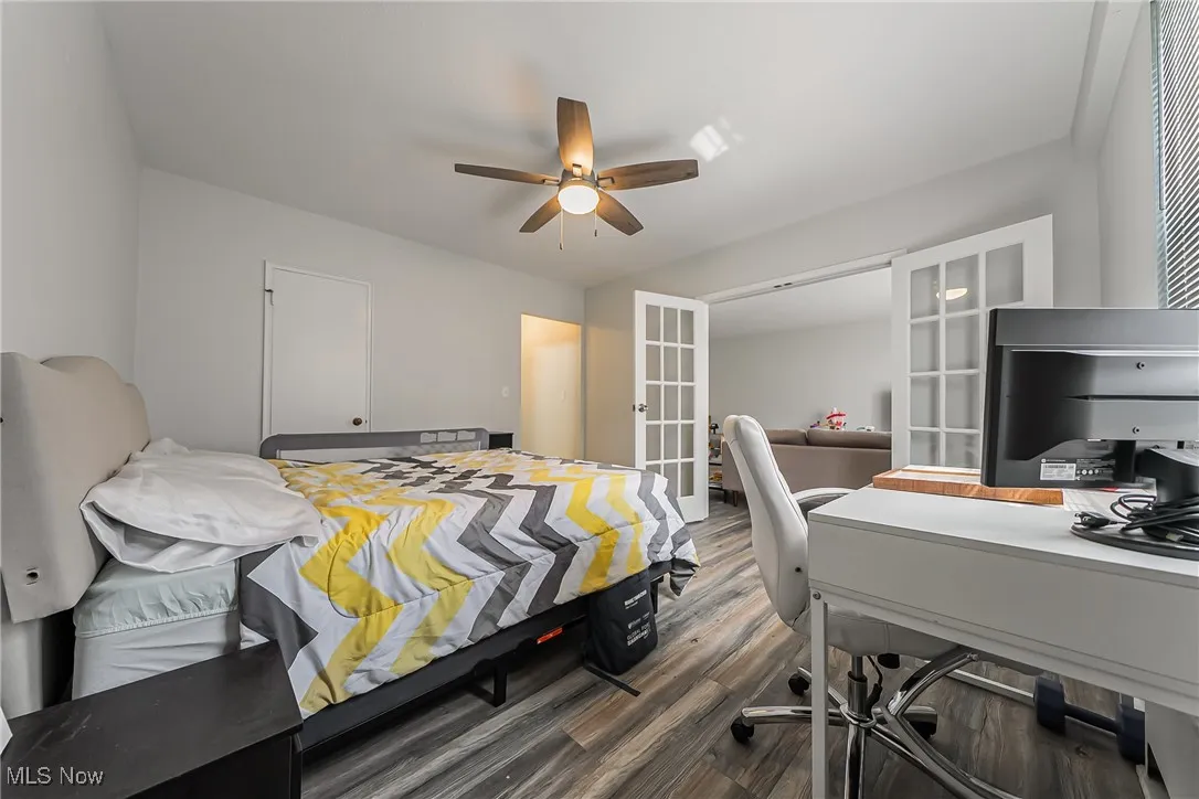 Bedroom with french doors, wood finished floors, a desk, and a ceiling fan