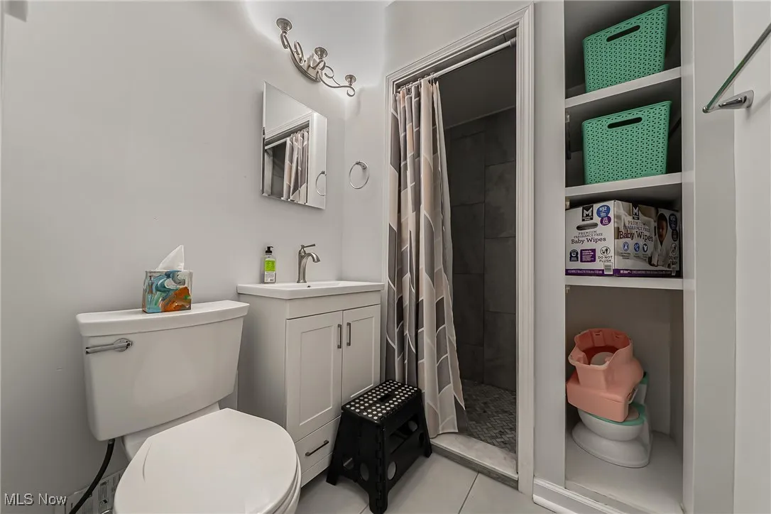 Full bath with a tile shower, vanity, and tile patterned floors