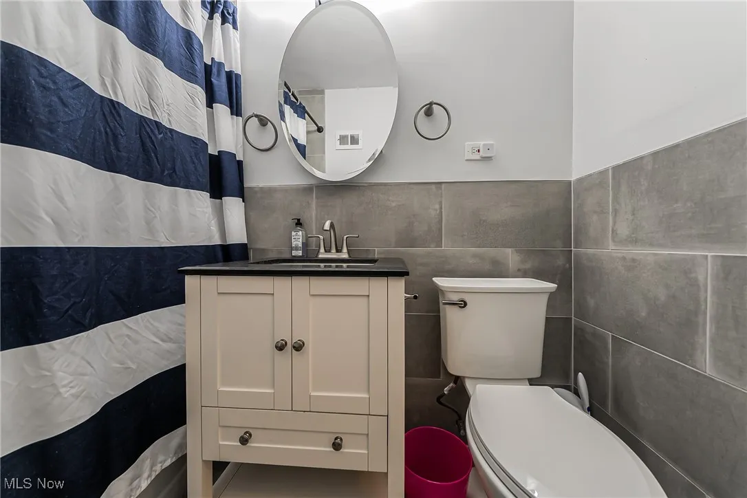 Full bathroom featuring tile walls and vanity