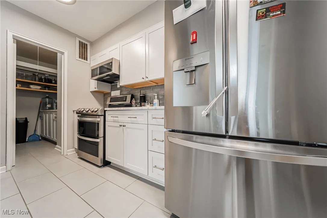Kitchen with appliances with stainless steel finishes, decorative backsplash, white cabinetry, and light countertops