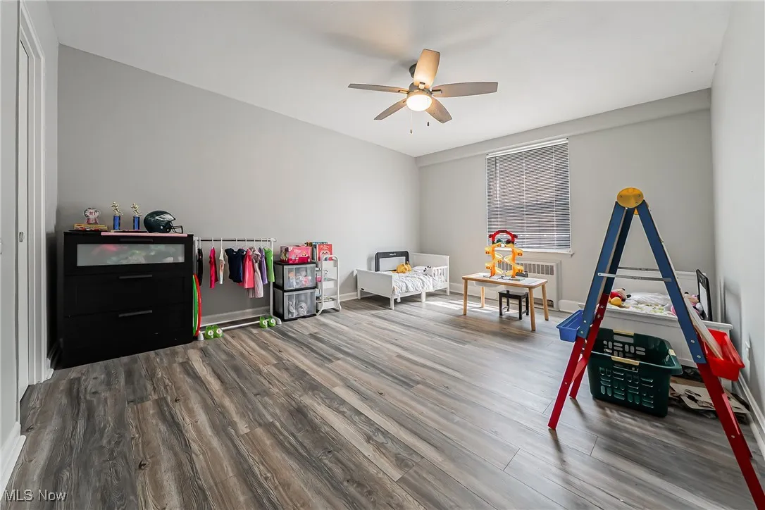 Game room with wood finished floors, ceiling fan, and radiator heating unit