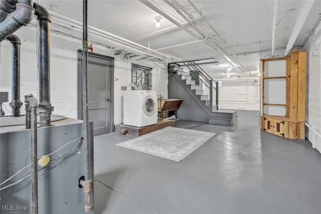 Unfinished basement with washer / clothes dryer, stairs, and a sink