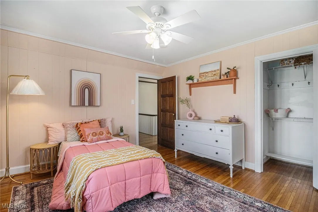 Bedroom with wood-type flooring, crown molding, and ceiling fan