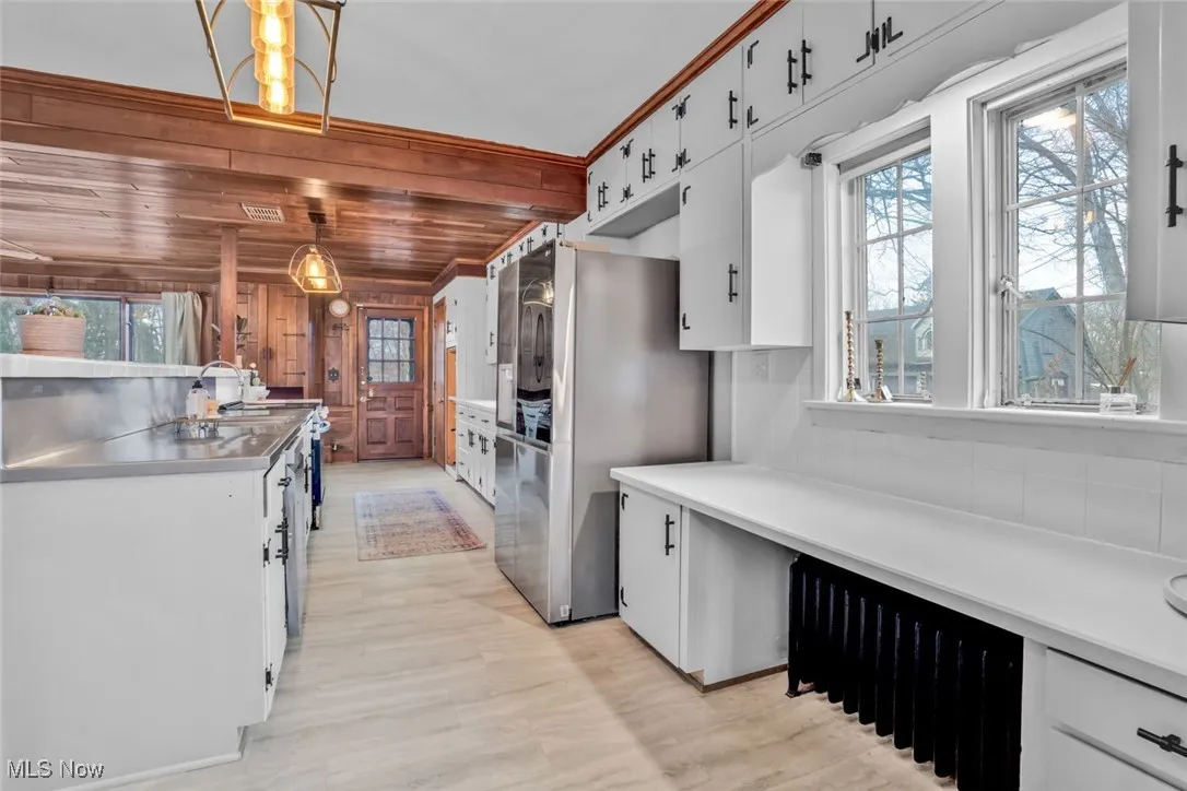 Kitchen with stainless steel countertops, light wood-style floors, white cabinetry, smart refrigerator, and decorative light fixtures