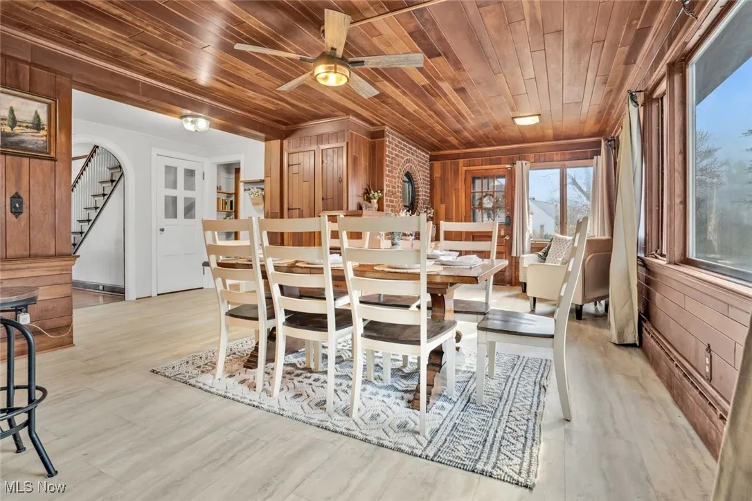 Dining area with wooden ceiling, wooden walls, stairs, light wood-type flooring, and a ceiling fan