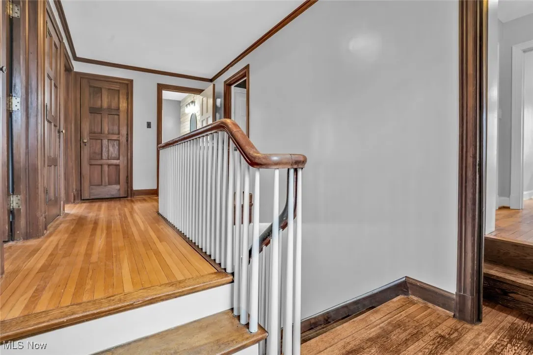 Staircase featuring hardwood / wood-style flooring, ornamental molding, and baseboards