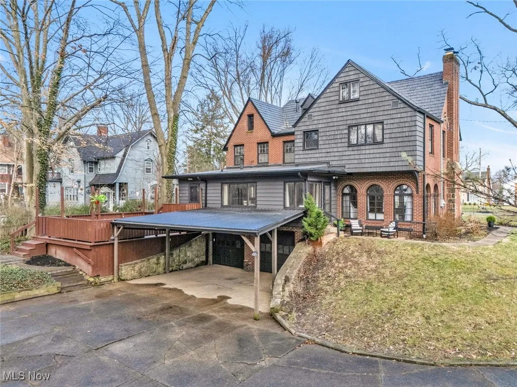View of front of house with brick siding, a chimney, concrete driveway, a carport, and a wooden deck