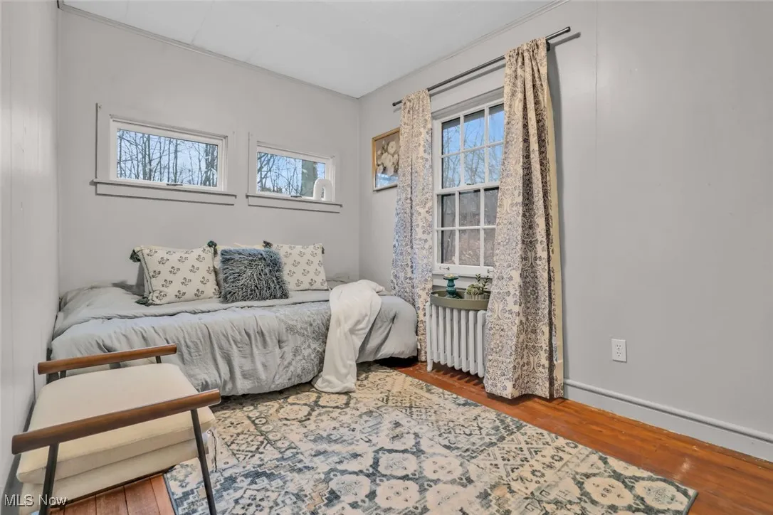 Bedroom featuring radiator, wood finished floors, and baseboards