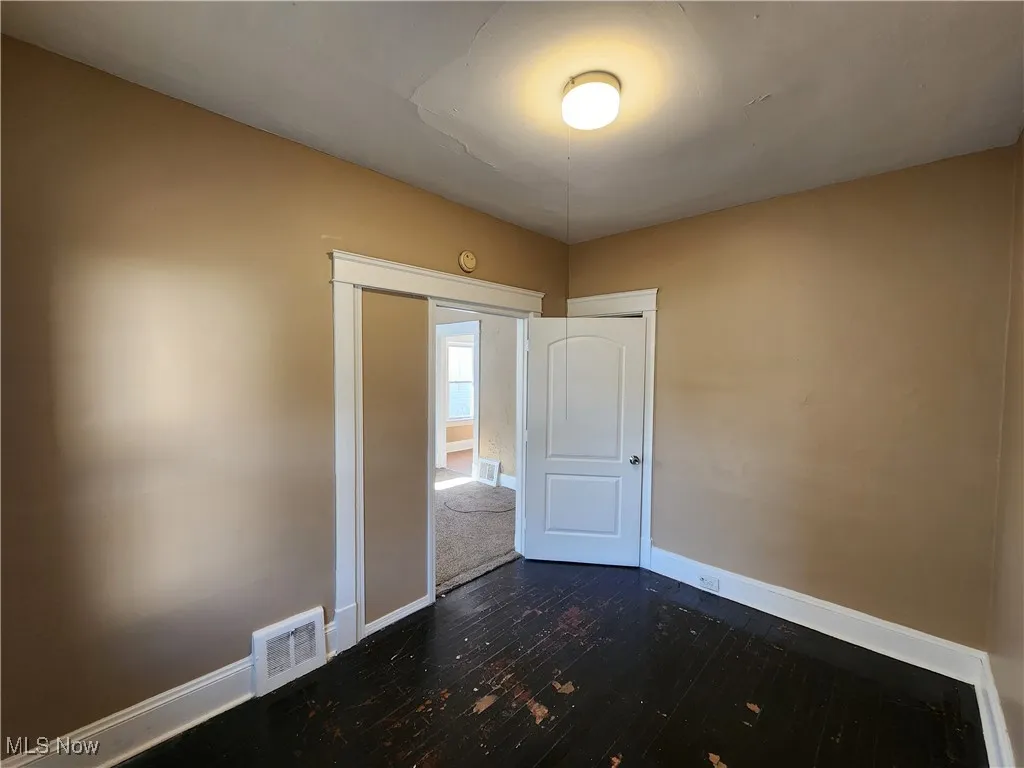 Unfurnished bedroom with baseboards and dark wood-style floors