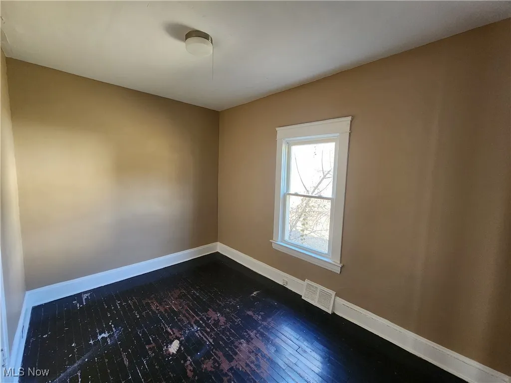 Spare room featuring dark wood-type flooring and baseboards