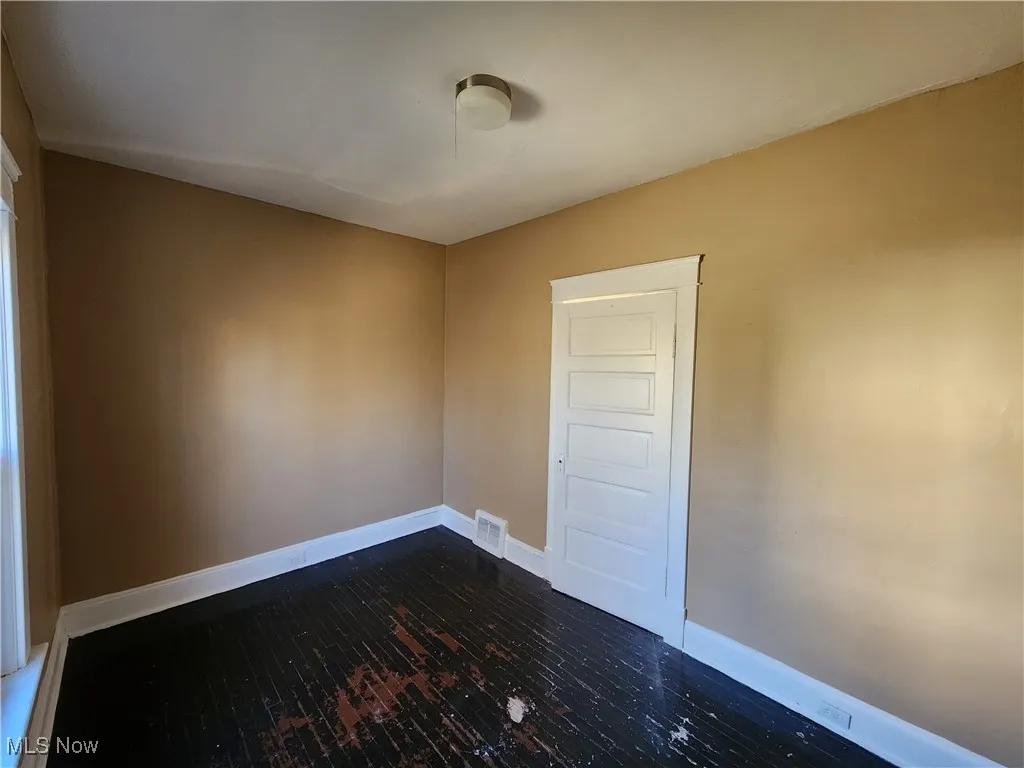 Empty room with baseboards and dark wood-style flooring