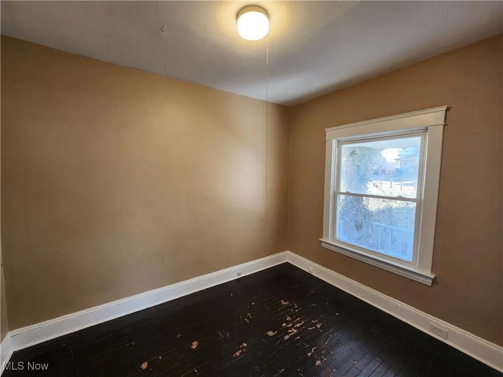 Spare room with baseboards and dark wood-style floors