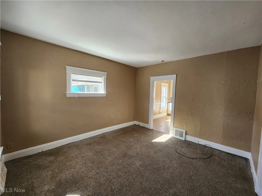 Carpeted empty room with healthy amount of natural light, a textured wall, and baseboards