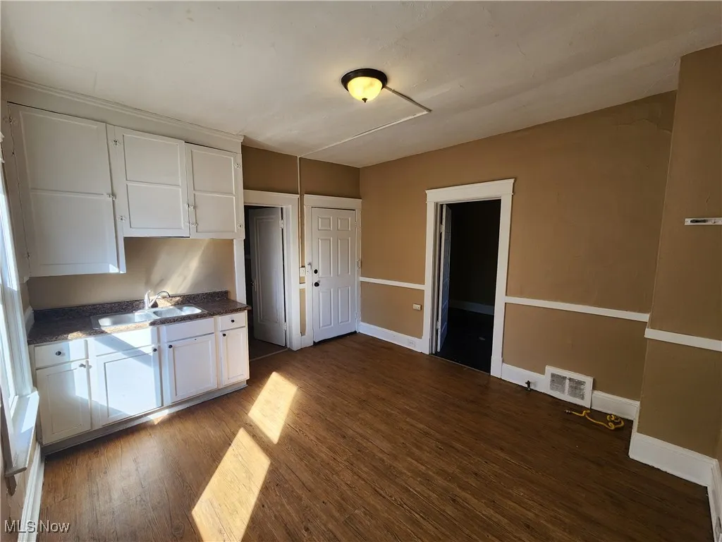 Kitchen featuring a sink, dark wood finished floors, white cabinetry, and baseboards