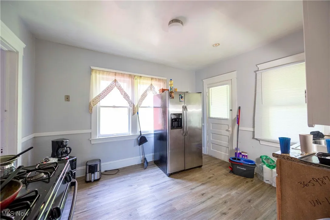 Kitchen with stainless steel fridge, range with gas cooktop, light wood-style flooring, and baseboards