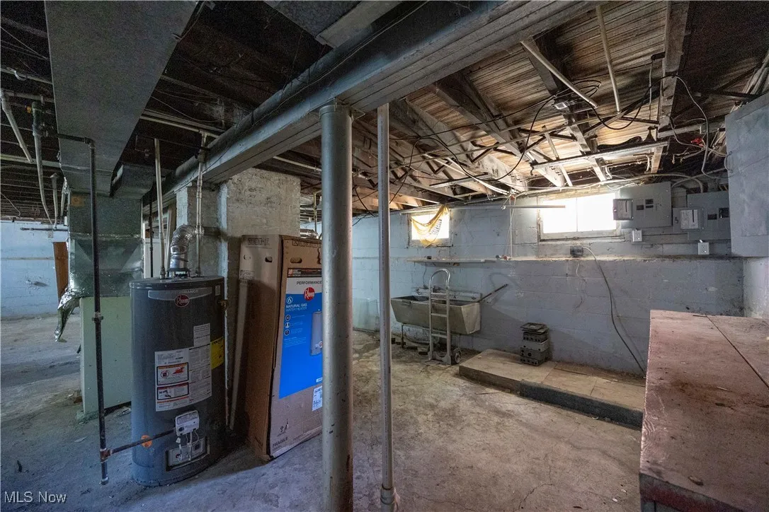 Below grade area with water heater, electric panel, and a sink