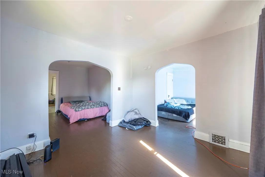 Living Room/ View of bedroom with arched walkways, wood finished floors, and baseboards