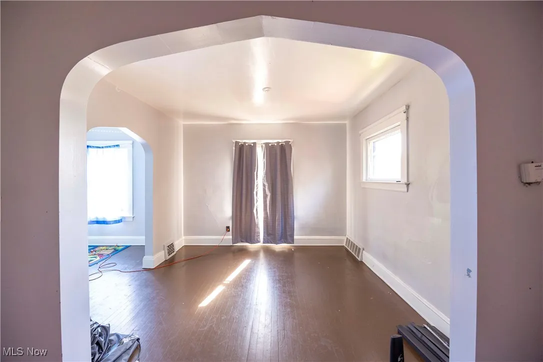 Spare room with baseboards, wood finished floors, and arched walkways